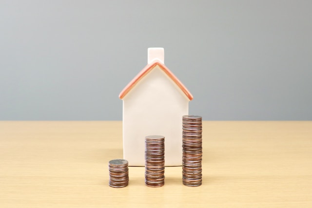 Rent money piled up in front of a small model of a house